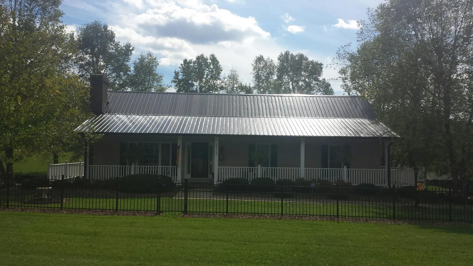 Gray metal roof on a brick ranch with a full width front porch — Gutter Guard Installation work by our crew in Bradford